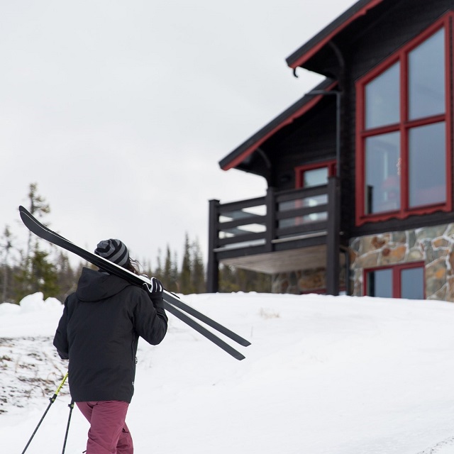 Kvinna framför fjällstuga 