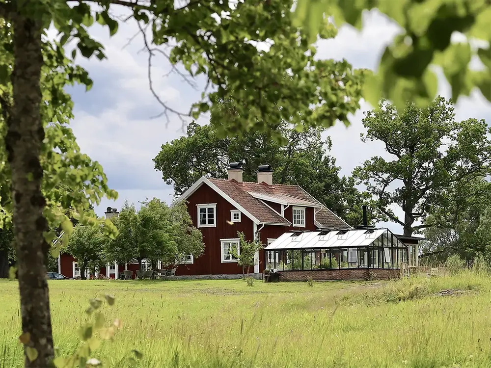 Rött hus omgivet av träd och åker